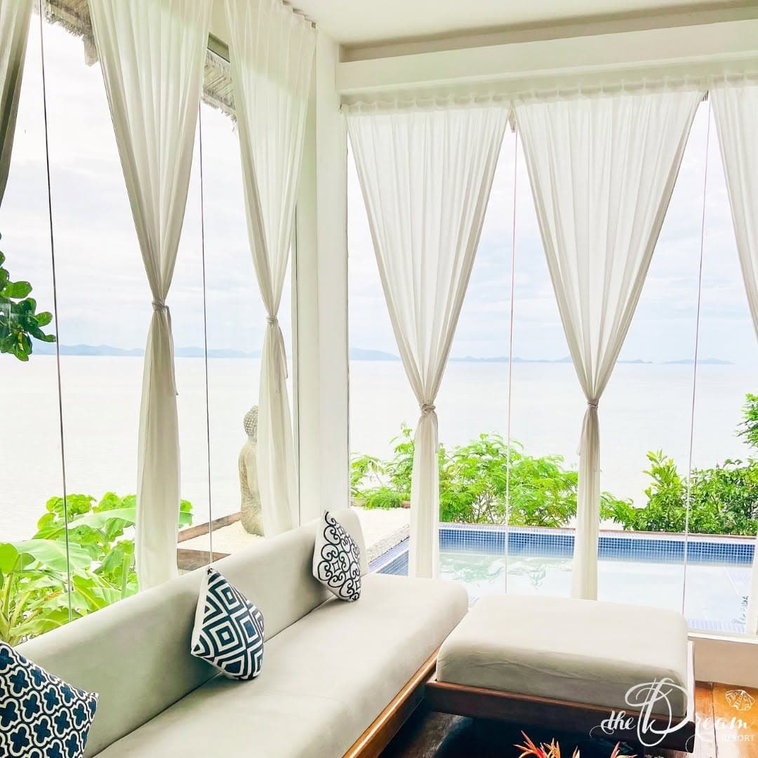 The Dreamers suite living area with sheer curtains and the sea past the glass