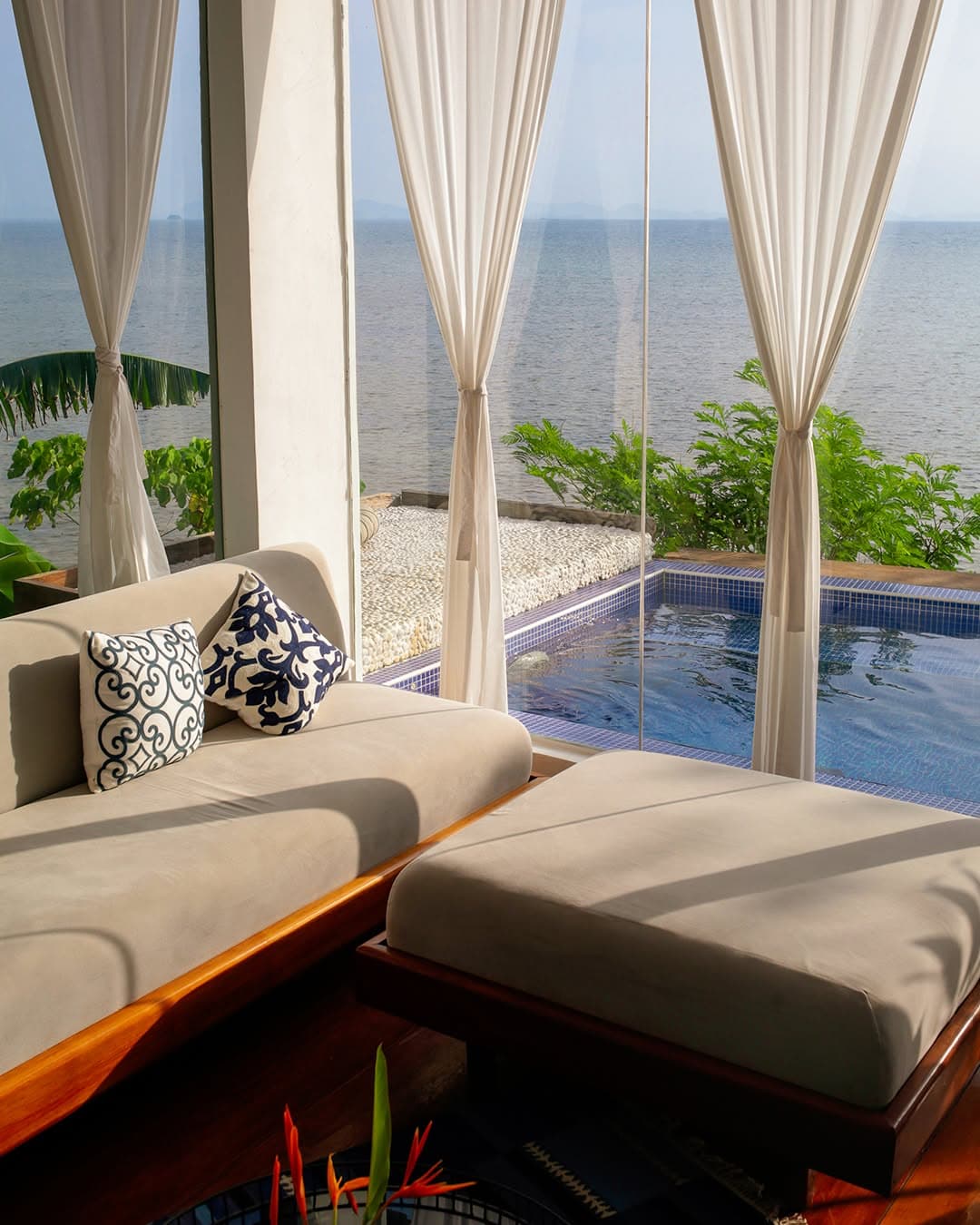 Villa daybed behind sheer curtains with plunge pool and sea beyond